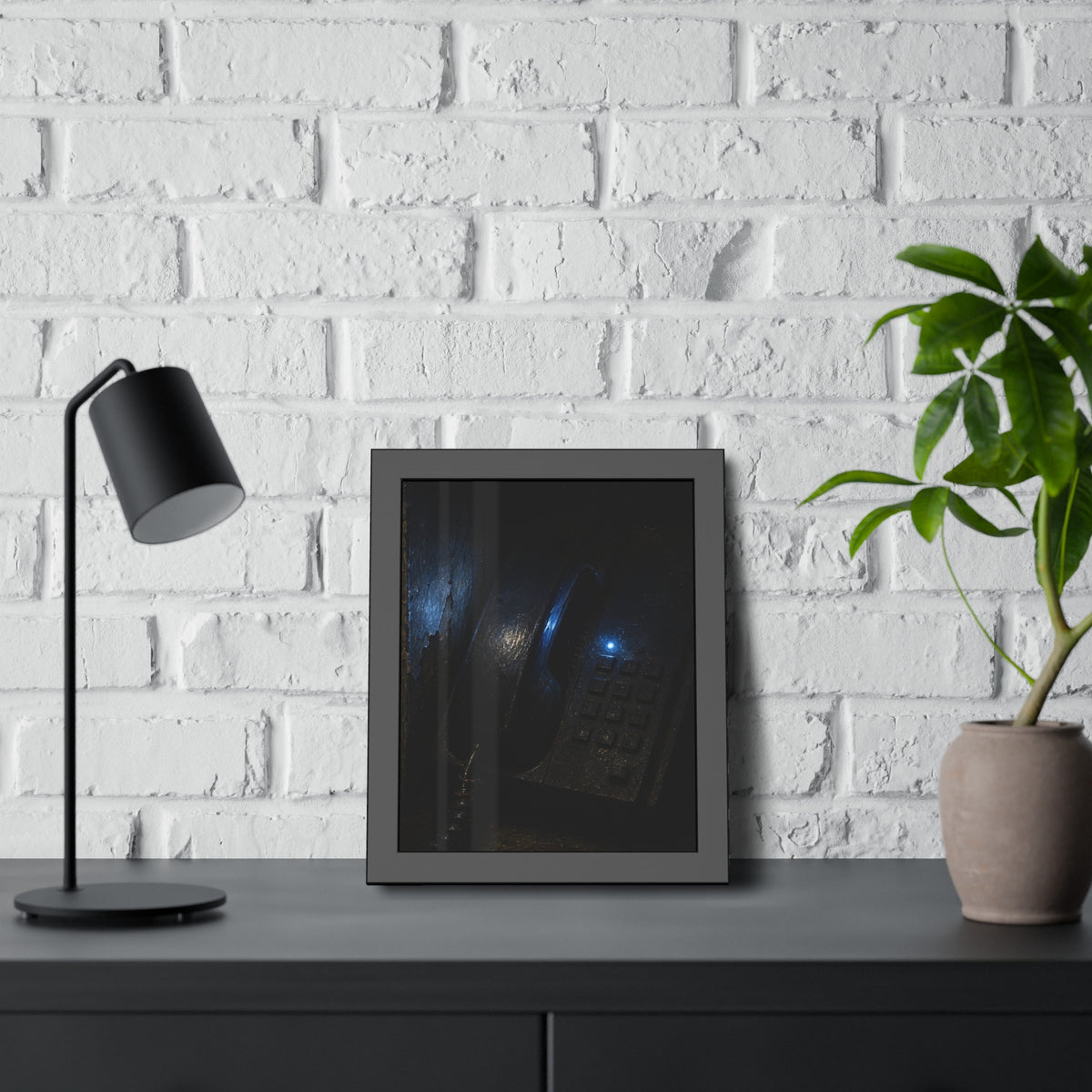 A grimy wall telephone in darkness with one small blue indicator light. The Night Queue by Garabaggio, framed fine art print hanging in a room.