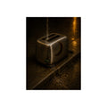 A toaster on a wet curb with water pouring into its slots. Rain Through the Slots by Garabaggio, fine art print, 12″ x 16″.