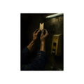 Weathered hands holding a paper queue ticket under a fluorescent tube. The First Number by Garabaggio, fine art print, 12″ x 16″.