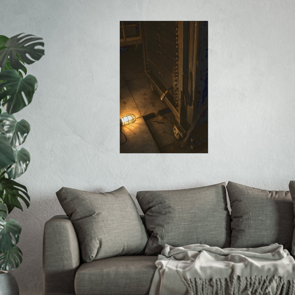 A server rack on a concrete floor beside a caged work light. The Silence at Cutover by Garabaggio, fine art print hanging in a room.