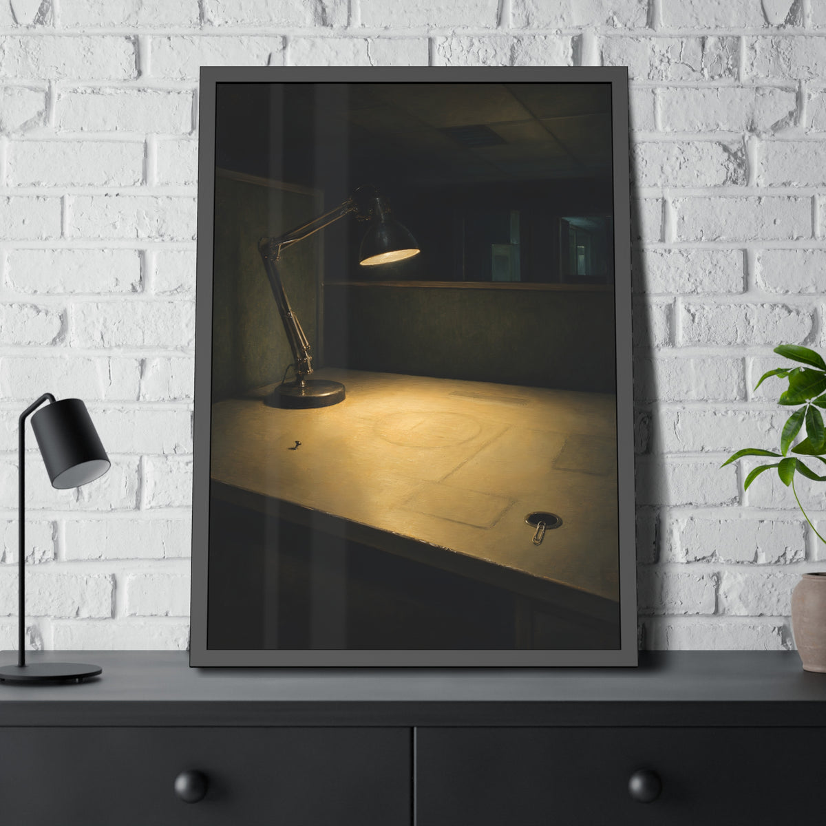 A lit desk lamp on an emptied office desk at night. The Desk Lamp Still Warm by Garabaggio, framed fine art print hanging in a room.