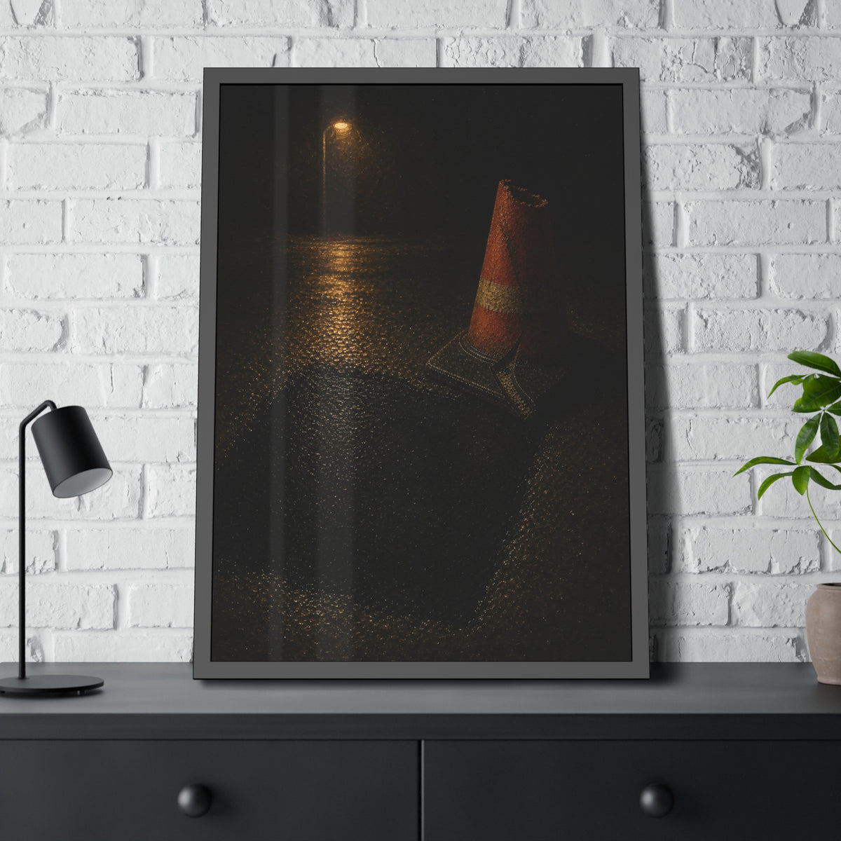 A traffic cone beside a fresh asphalt patch under a street lamp. The Sentinel After Repair by Garabaggio, framed fine art print hanging in a room.