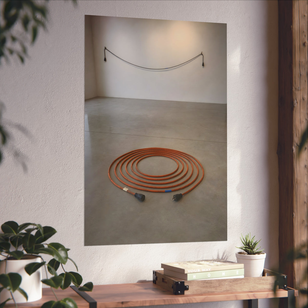 An orange extension cord coiled in a spiral on a bare gallery floor. The Floor Coil by Garabaggio, fine art print hanging in a room.