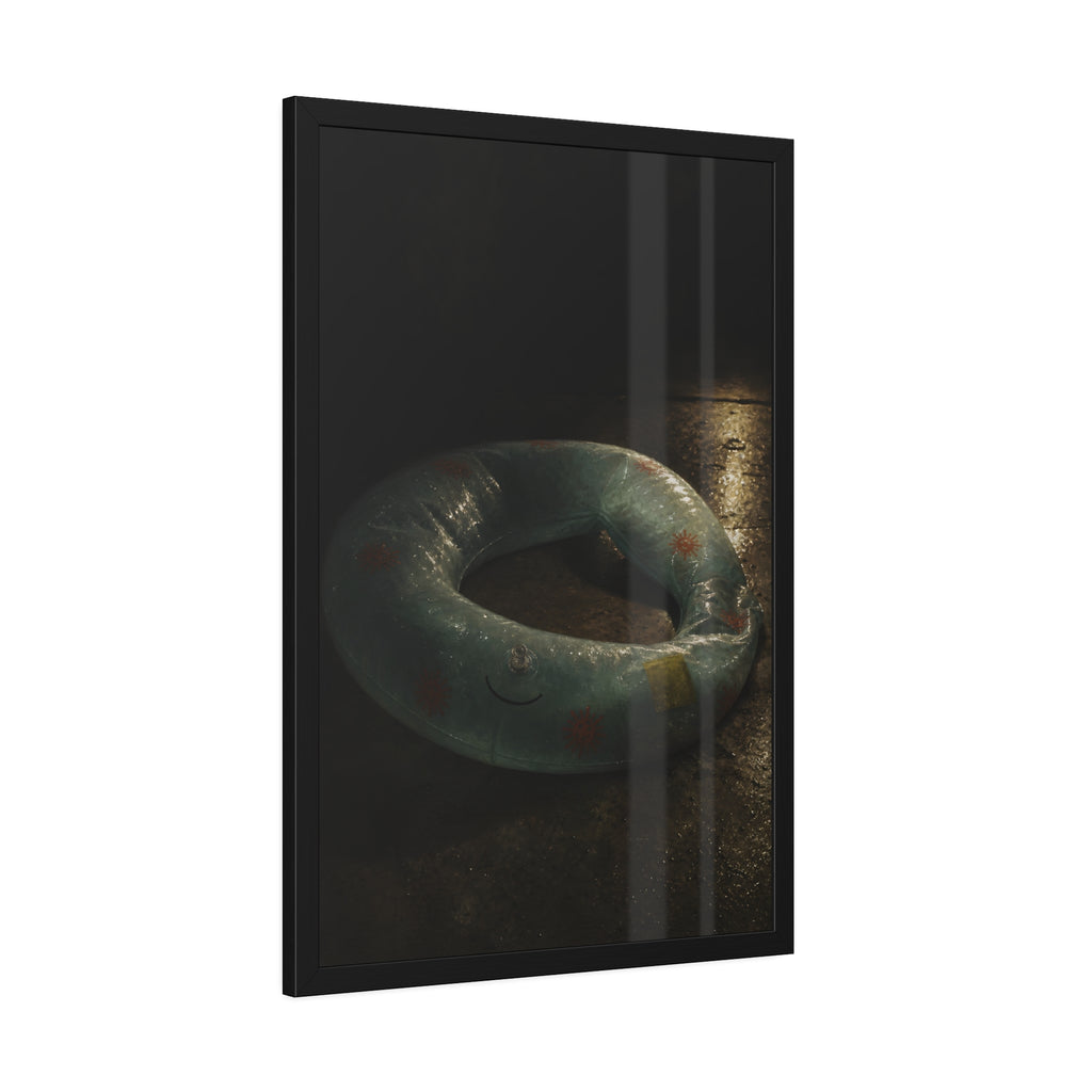 Deflated pool float ring on wet ground, lit from one side in the dark. After the Last Swim by Garabaggio, framed fine art print hanging in a room.