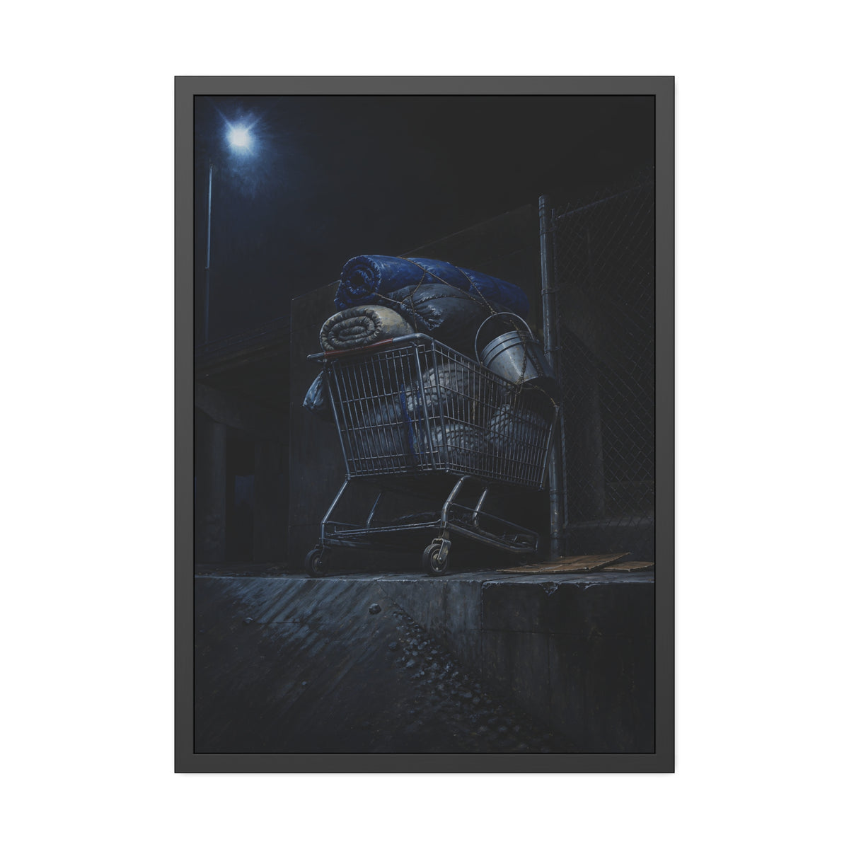 A shopping cart piled with bedding and buckets under a streetlamp. The Loading of Another Life by Garabaggio, framed fine art print, 28″ x 40″.