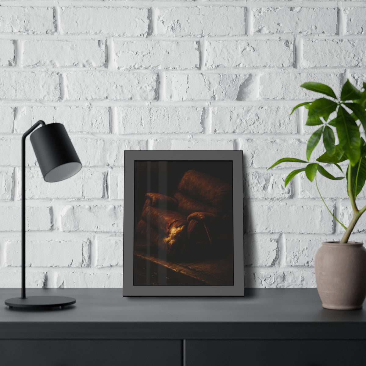 A torn brown recliner tipped on a curb in dim warm light. The Deposition of the Broken Recliner by Garabaggio, framed fine art print hanging in a room.