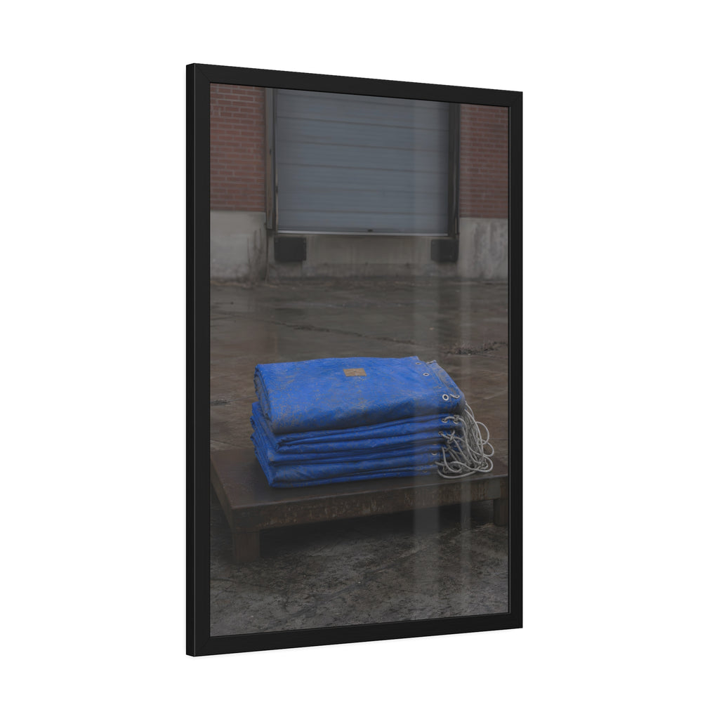 A folded blue tarp stacked on a low wooden platform by a loading dock. The Repaired Fold by Garabaggio, framed fine art print hanging in a room.