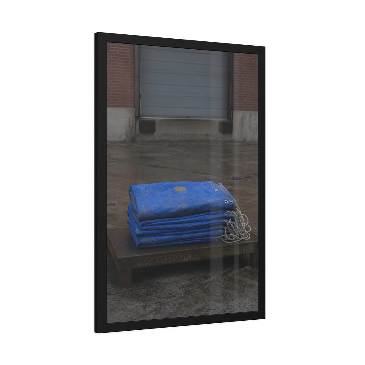 A folded blue tarp stacked on a low wooden platform by a loading dock. The Repaired Fold by Garabaggio, framed fine art print hanging in a room.