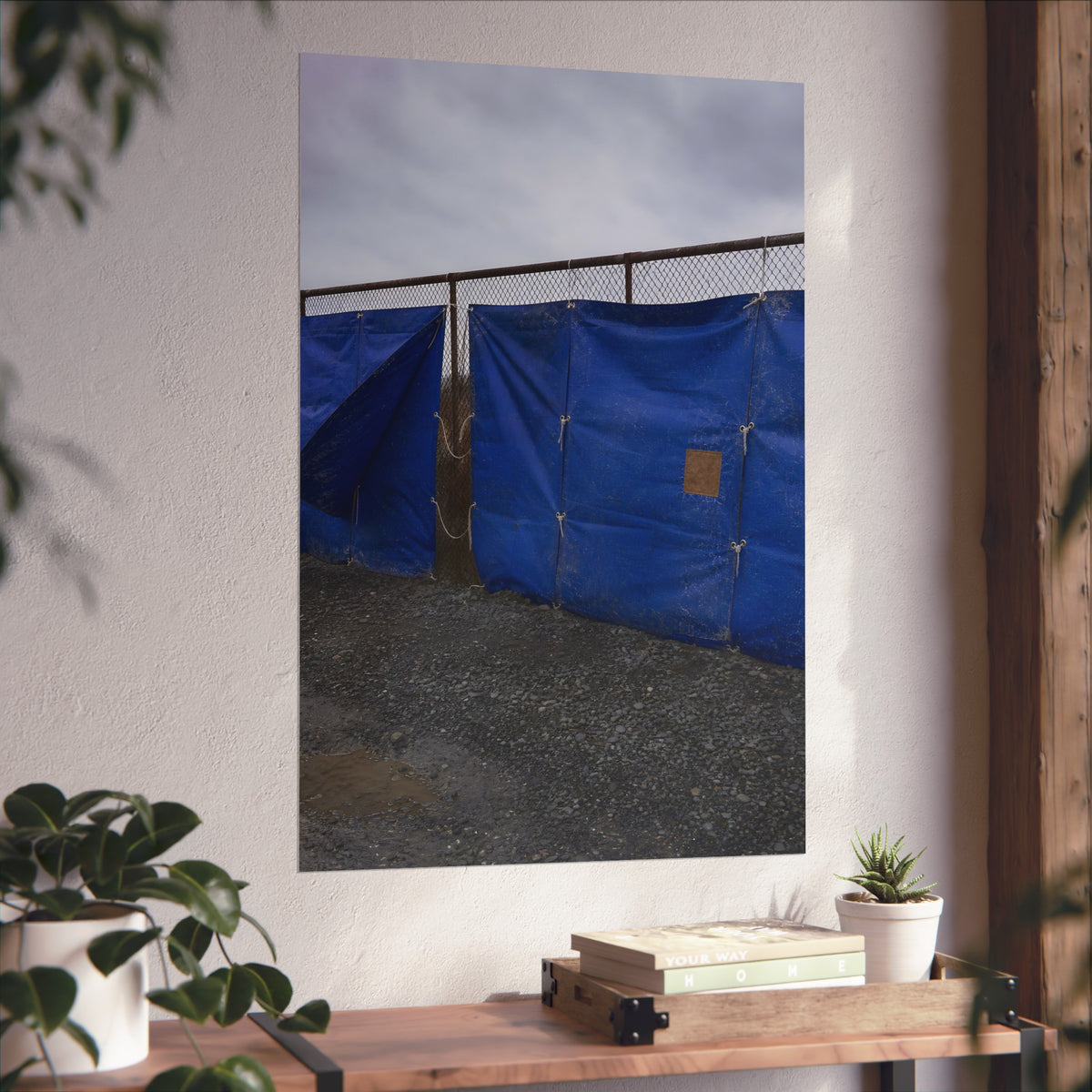 Blue tarps lashed to a chain link fence above gravel under grey sky. Drapery on the Fence by Garabaggio, fine art print hanging in a room.