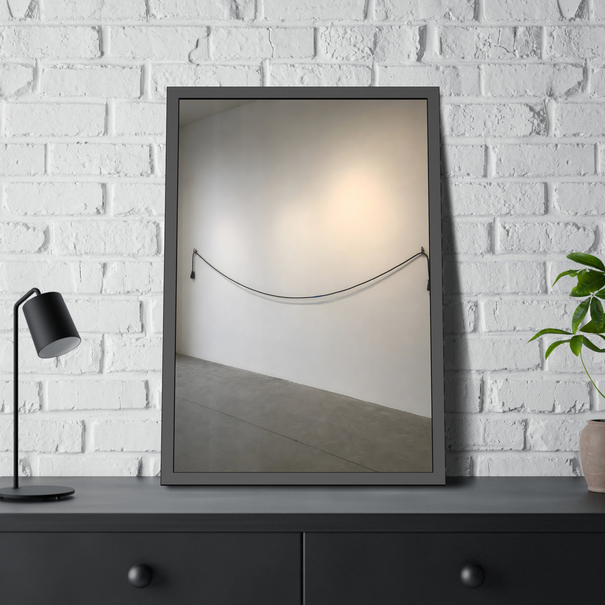 An extension cord hung in a long slack curve across a bare white wall. The Unplugged Line by Garabaggio, framed fine art print hanging in a room.