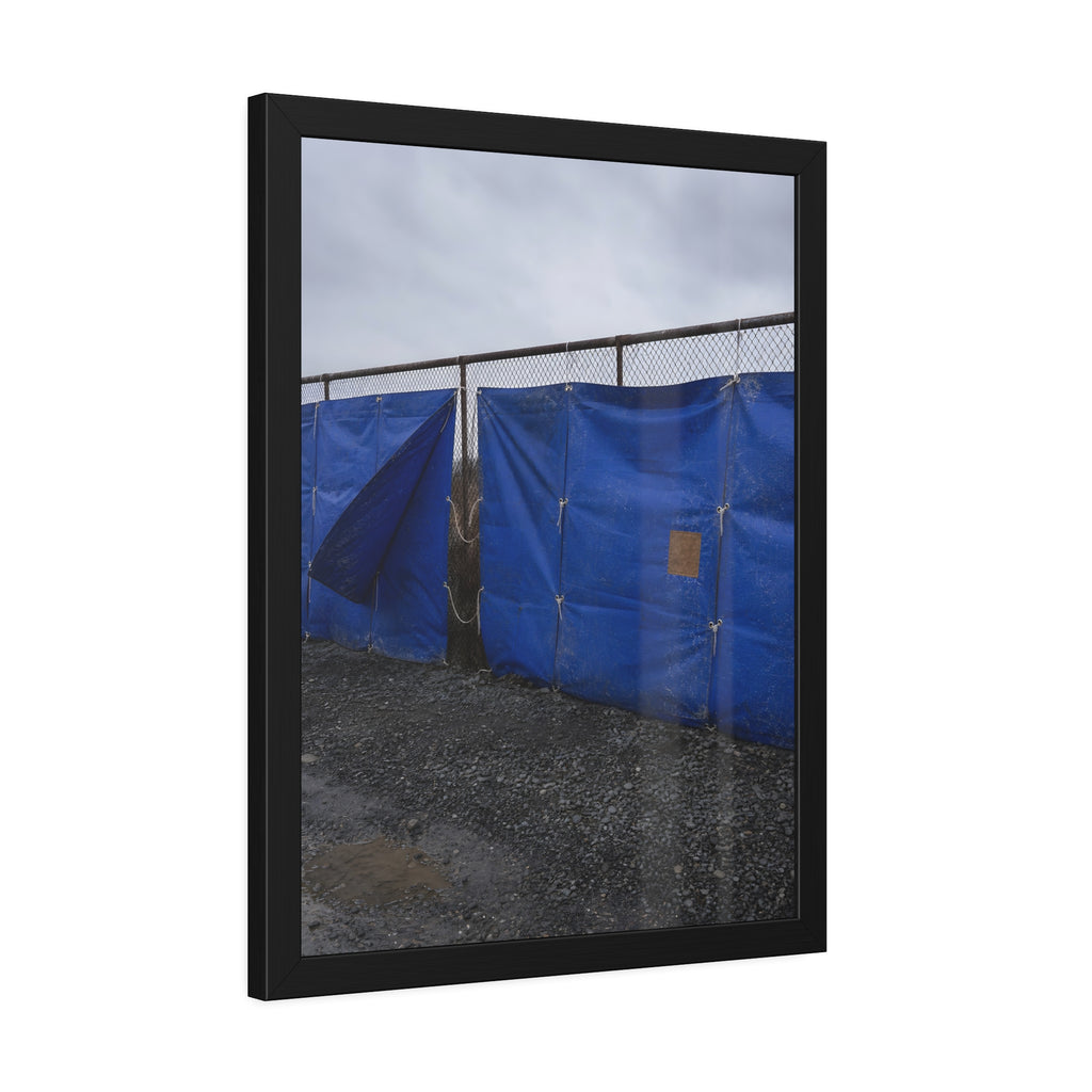Blue tarps lashed to a chain link fence above gravel under grey sky. Drapery on the Fence by Garabaggio, framed fine art print hanging in a room.