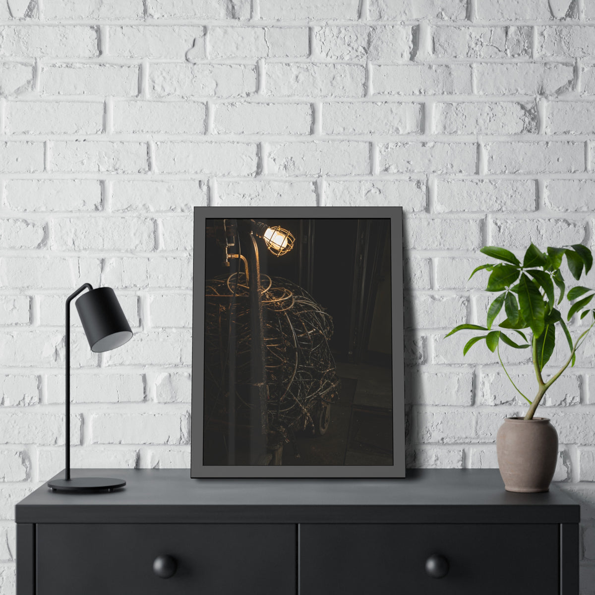 A tangled ball of cables on a hand cart under a caged work lamp. The Cable Harvest by Garabaggio, framed fine art print hanging in a room.